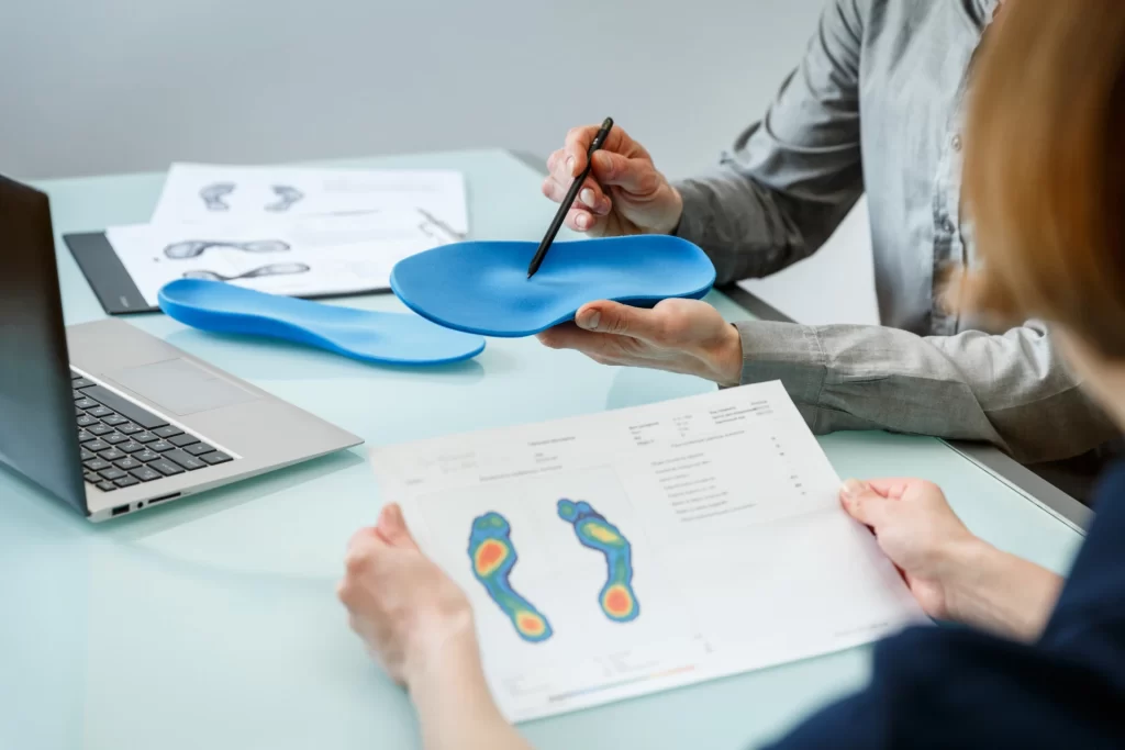 Paper showing foot scan and doctor pointing to insole with a pen