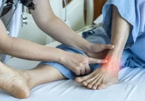 Doctor touching patient's ankle showing red from osteoarthritis pain