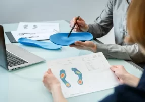 Paper showing foot scan and doctor pointing to insole with a pen